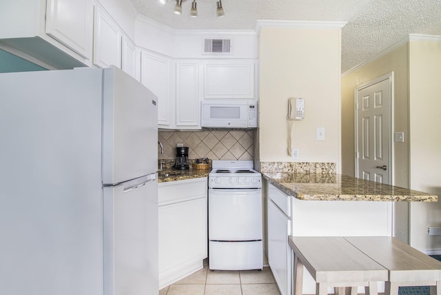 kitchen featuring white cabinets, white appliances, kitchen peninsula, and dark stone counters