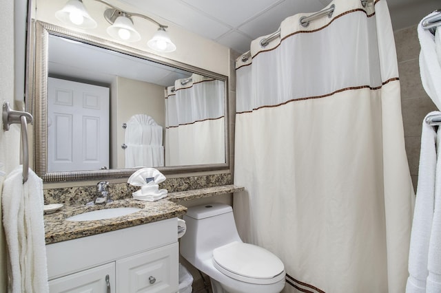 bathroom with a paneled ceiling, vanity, and toilet