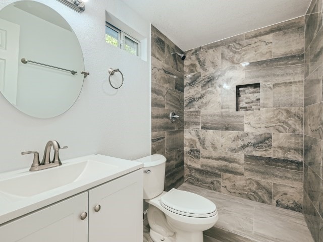 bathroom featuring vanity, toilet, and tiled shower