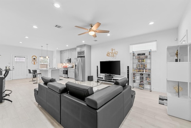 living room with ceiling fan, sink, and light hardwood / wood-style flooring