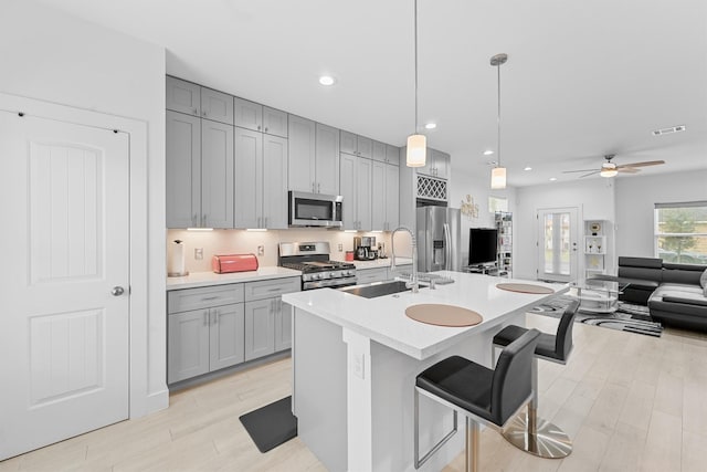 kitchen featuring sink, hanging light fixtures, a breakfast bar area, ceiling fan, and stainless steel appliances