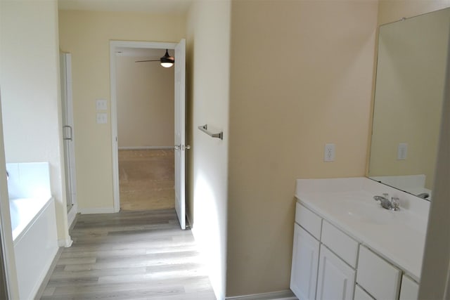 bathroom featuring hardwood / wood-style flooring, ceiling fan, a tub, and vanity