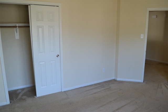 unfurnished bedroom featuring light colored carpet and a closet