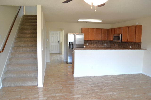 kitchen with appliances with stainless steel finishes, backsplash, and ceiling fan