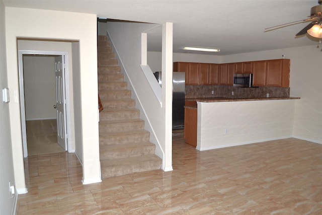 kitchen with ceiling fan, decorative backsplash, kitchen peninsula, and appliances with stainless steel finishes