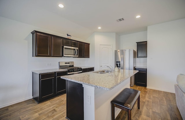 kitchen featuring dark brown cabinetry, sink, light hardwood / wood-style flooring, a kitchen island with sink, and appliances with stainless steel finishes