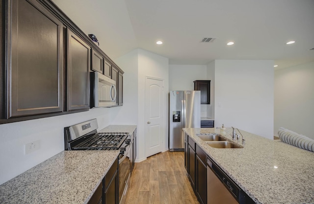 kitchen featuring sink, light stone countertops, light hardwood / wood-style floors, dark brown cabinetry, and stainless steel appliances