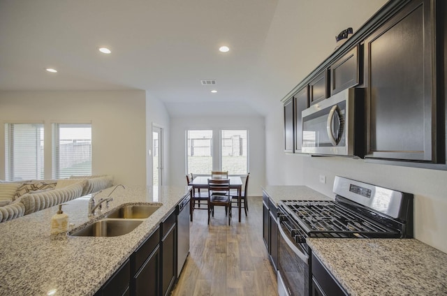 kitchen featuring light stone countertops, appliances with stainless steel finishes, dark brown cabinets, sink, and dark hardwood / wood-style floors