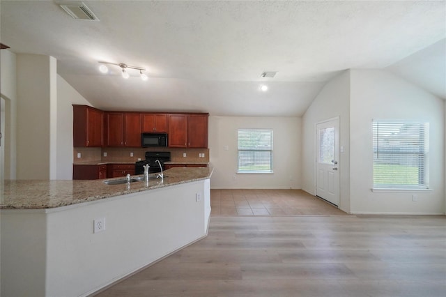 kitchen with light stone countertops, light wood-type flooring, sink, black appliances, and lofted ceiling