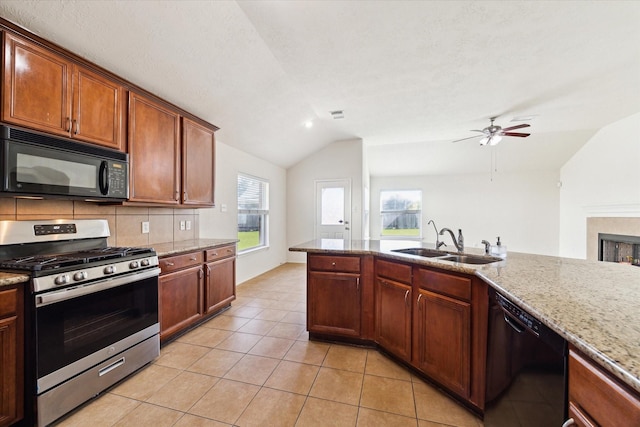 kitchen featuring sink, tasteful backsplash, lofted ceiling, light tile patterned flooring, and black appliances