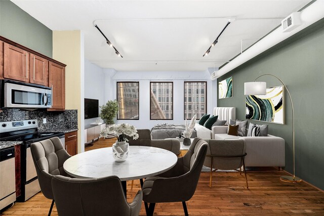 dining space with wood-type flooring and track lighting