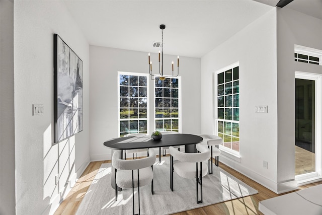 dining room with light hardwood / wood-style flooring and an inviting chandelier