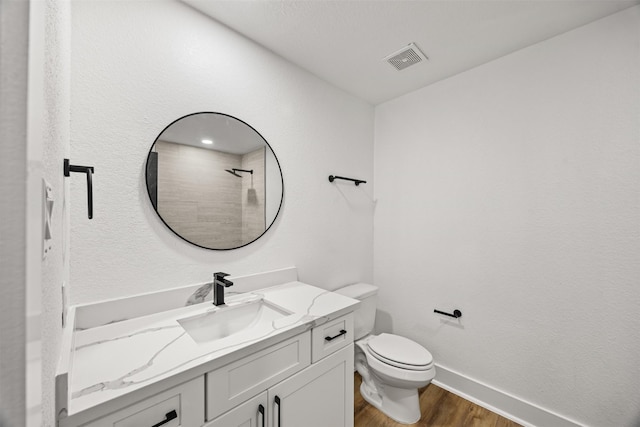 bathroom featuring hardwood / wood-style flooring, vanity, toilet, and walk in shower