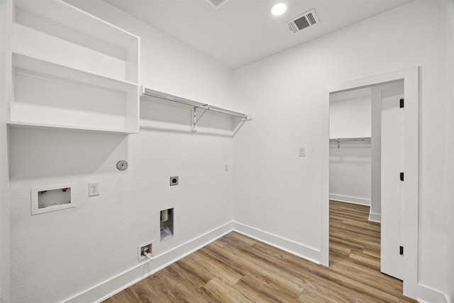 clothes washing area featuring wood-type flooring, hookup for a washing machine, hookup for a gas dryer, and electric dryer hookup