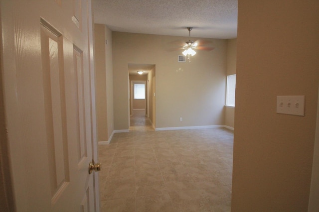 unfurnished room with a wealth of natural light, ceiling fan, and a textured ceiling