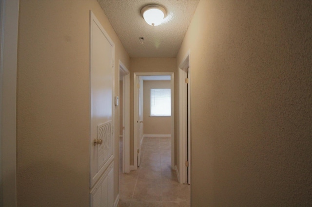 hallway featuring light tile patterned floors and a textured ceiling