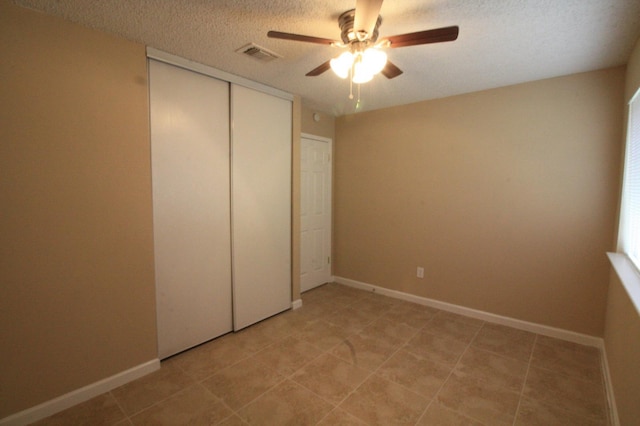 unfurnished bedroom with ceiling fan, a textured ceiling, and a closet