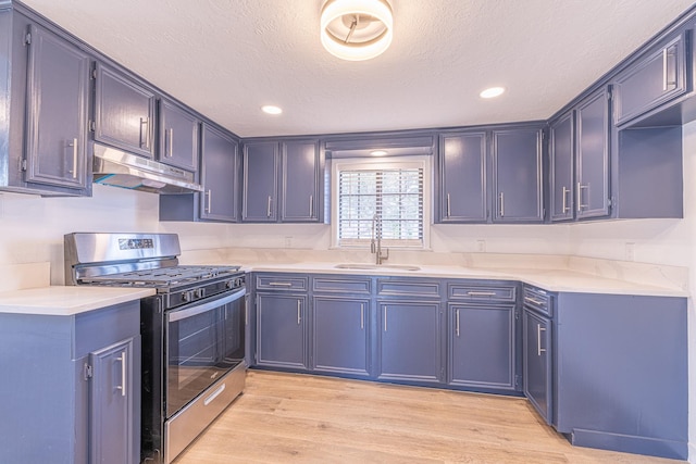 kitchen with sink, blue cabinets, light hardwood / wood-style floors, a textured ceiling, and stainless steel range with gas stovetop