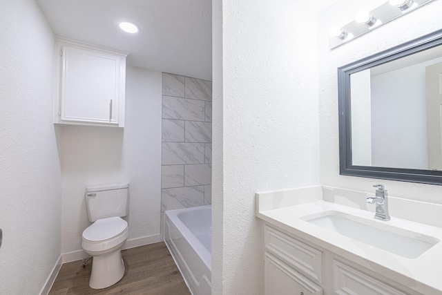 full bathroom with hardwood / wood-style flooring, vanity, toilet, and tiled shower / bath combo