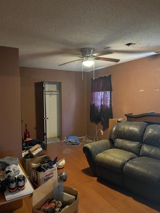 living room with ceiling fan, wood-type flooring, and a textured ceiling