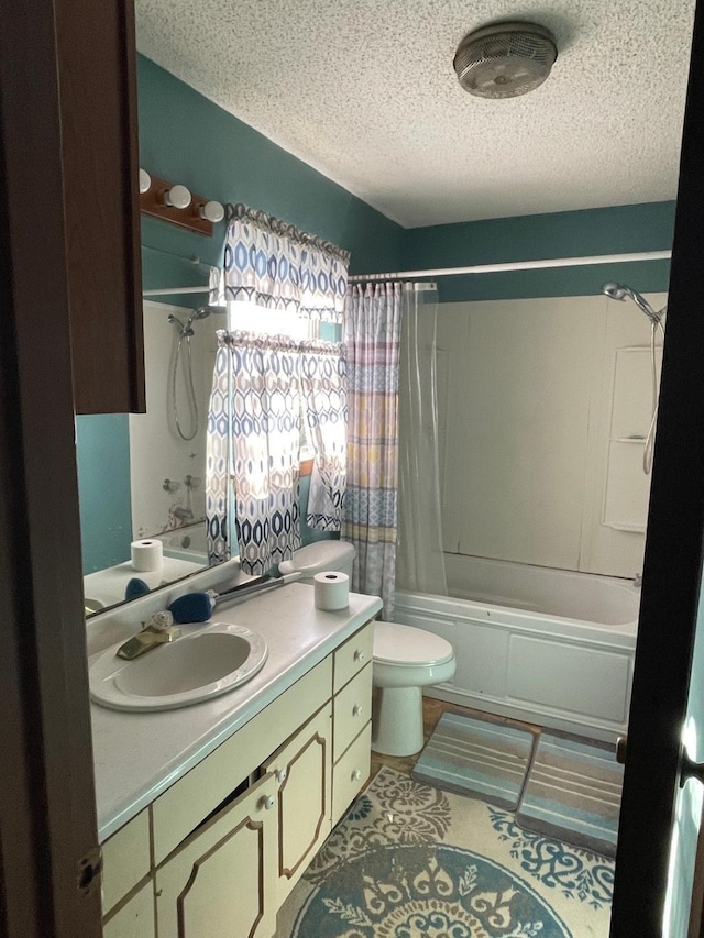 full bathroom featuring shower / bath combination with curtain, vanity, a textured ceiling, and toilet