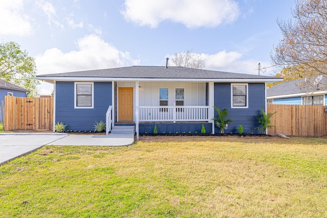 ranch-style home featuring covered porch and a front yard