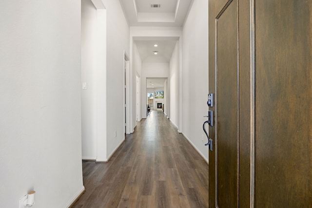 hall featuring a raised ceiling and dark wood-type flooring