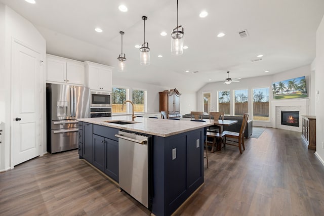 kitchen with appliances with stainless steel finishes, ceiling fan, sink, a center island with sink, and white cabinets