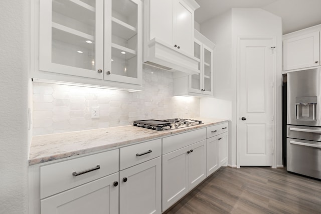 kitchen featuring dark wood-type flooring, light stone counters, backsplash, white cabinets, and appliances with stainless steel finishes