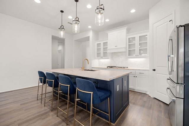 kitchen featuring white cabinetry, sink, hanging light fixtures, a kitchen island with sink, and appliances with stainless steel finishes