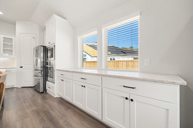 kitchen with white cabinets, stainless steel appliances, and vaulted ceiling