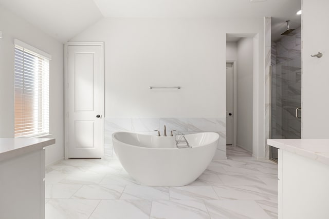 bathroom with shower with separate bathtub, vanity, vaulted ceiling, and tile walls