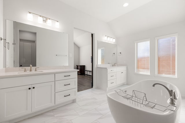 bathroom with vanity, lofted ceiling, and a tub