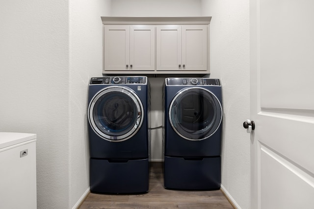 clothes washing area with cabinets, light hardwood / wood-style floors, and washer and clothes dryer