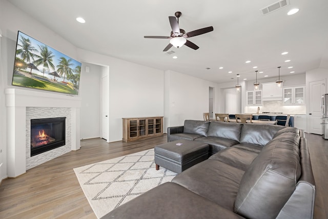 living room featuring ceiling fan, wood-type flooring, and a fireplace