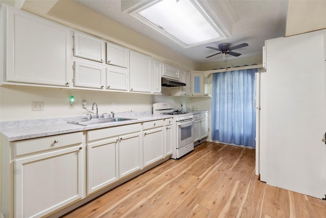 kitchen with light wood-type flooring, extractor fan, sink, white cabinetry, and white gas stove