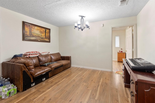 living room with light hardwood / wood-style flooring, a textured ceiling, and a notable chandelier