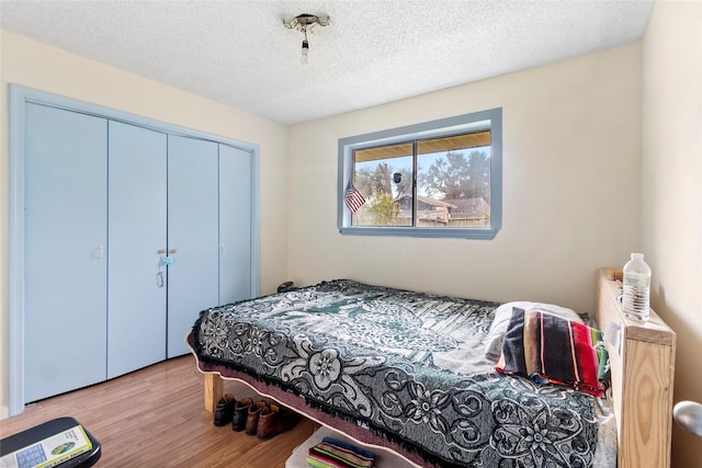 bedroom featuring a textured ceiling, light wood-type flooring, and a closet