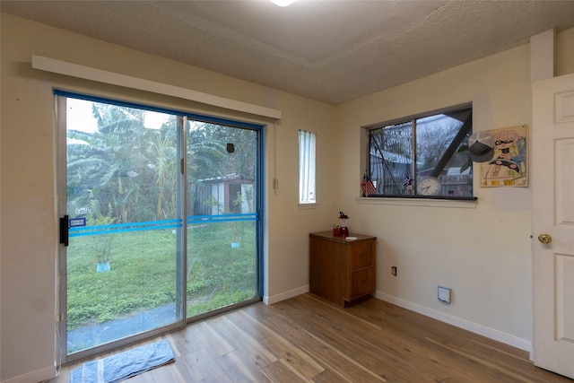 doorway to outside with hardwood / wood-style floors and a textured ceiling