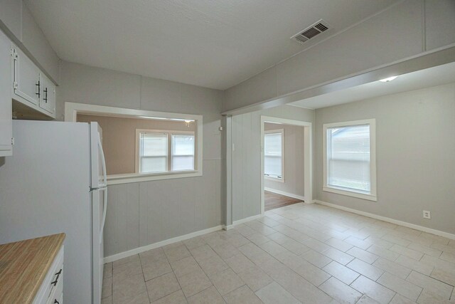 1202 14th Ave N, Texas City, TX 77590 - kitchen featuring white fridge, white cabinetry, and light tile patterned floors