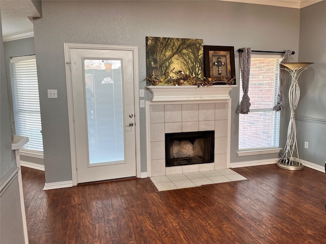 unfurnished living room with wood-type flooring, ornamental molding, and a tile fireplace