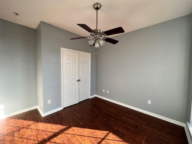 unfurnished bedroom with dark hardwood / wood-style flooring, a closet, and ceiling fan