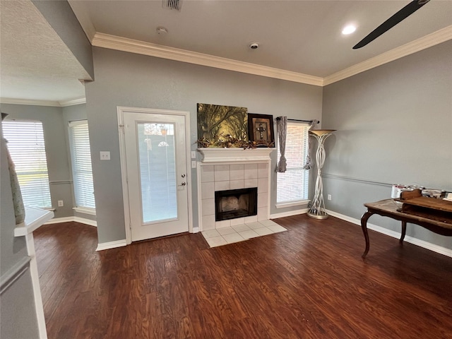 living room with a tiled fireplace, hardwood / wood-style flooring, and ornamental molding