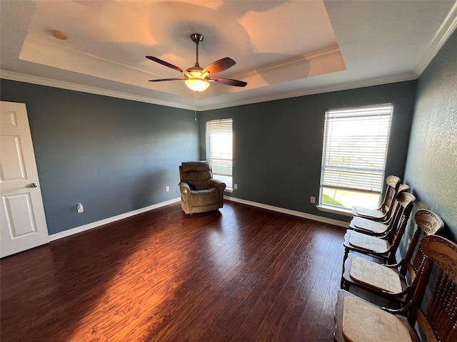 unfurnished room featuring ornamental molding, dark wood-type flooring, ceiling fan, and a tray ceiling