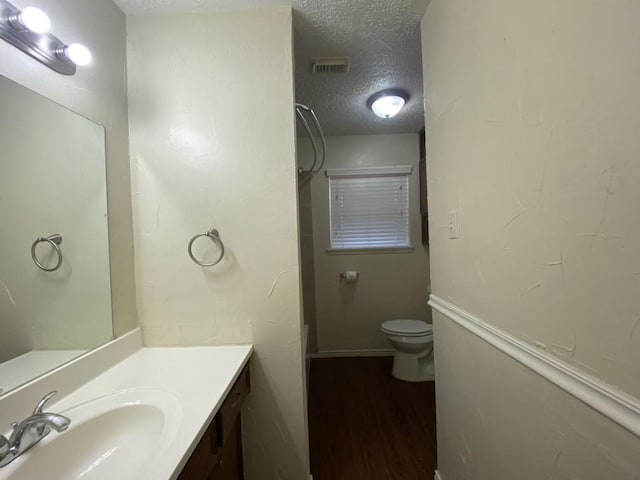 bathroom featuring vanity, toilet, wood-type flooring, and a textured ceiling