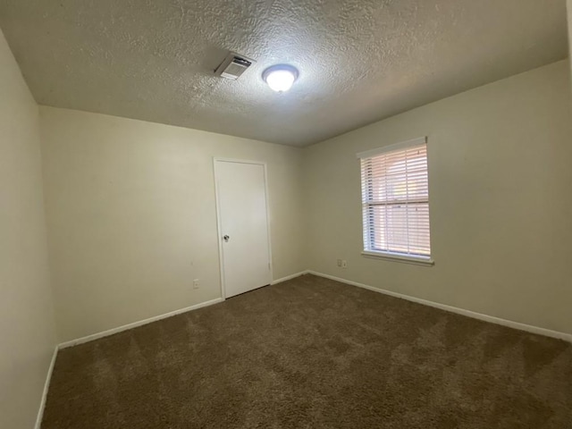 unfurnished room with dark carpet and a textured ceiling