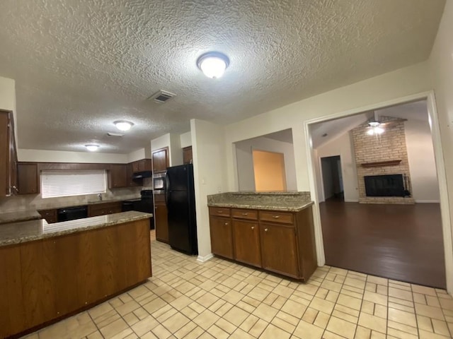 kitchen featuring black appliances, ceiling fan, a fireplace, a textured ceiling, and kitchen peninsula