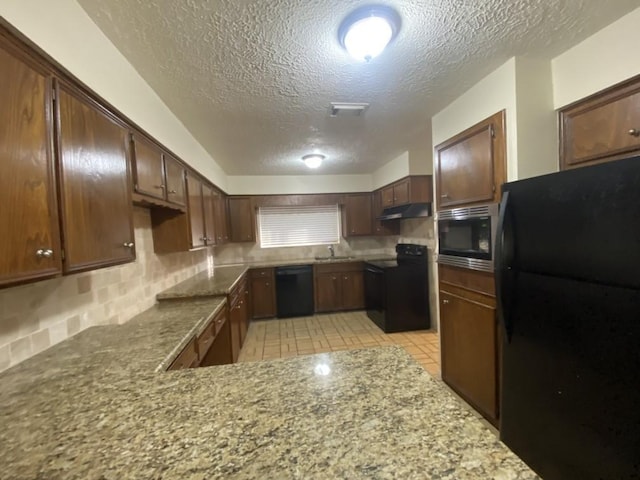 kitchen featuring kitchen peninsula, light tile patterned flooring, black appliances, and a textured ceiling