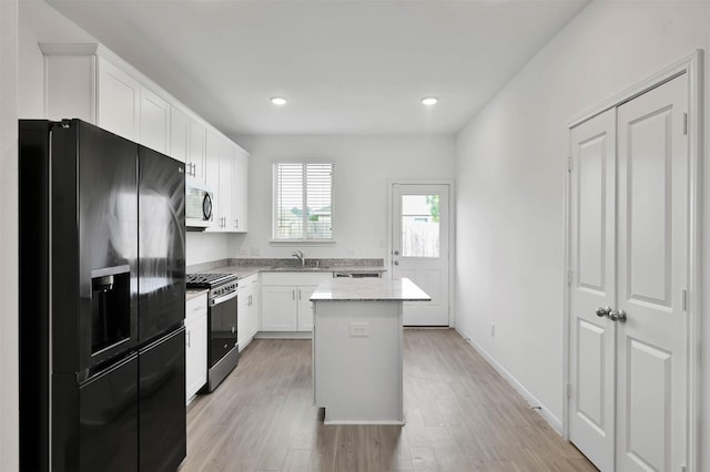 kitchen with white cabinetry, light hardwood / wood-style flooring, a kitchen island, and stainless steel appliances