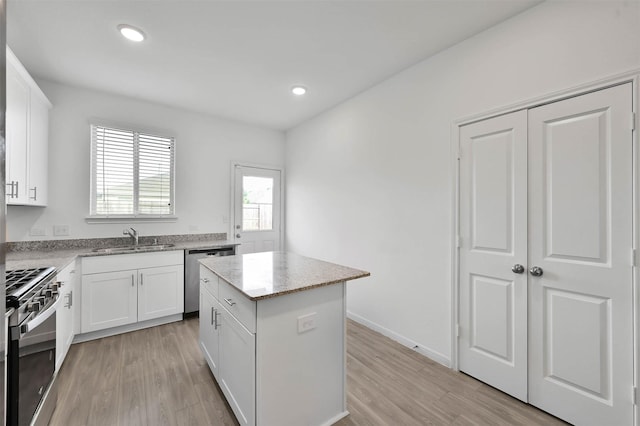 kitchen featuring white cabinets, appliances with stainless steel finishes, a center island, and sink